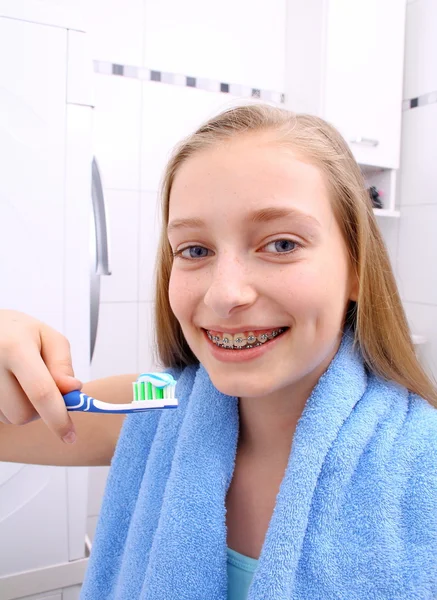 Ragazza bionda con l'apparecchio sorridente mentre ti lavi i denti — Foto Stock