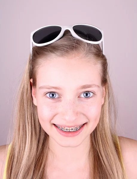 Sorrindo menina loira com aparelho e óculos de sol — Fotografia de Stock