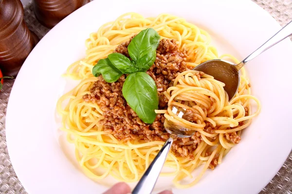 Comer espaguetis boloñesa con cuchara y tenedor — Foto de Stock