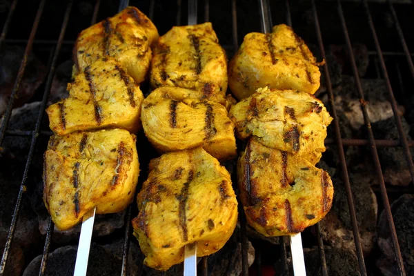 Curry marinated chicken breast grilling on metal skewers — Stock Photo, Image