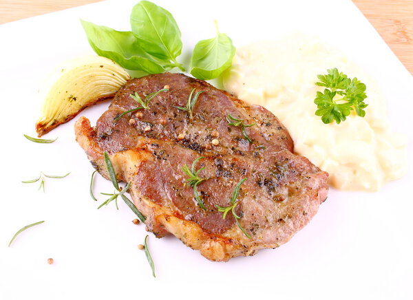 Grilled steak meat with onion, potato salad, basil