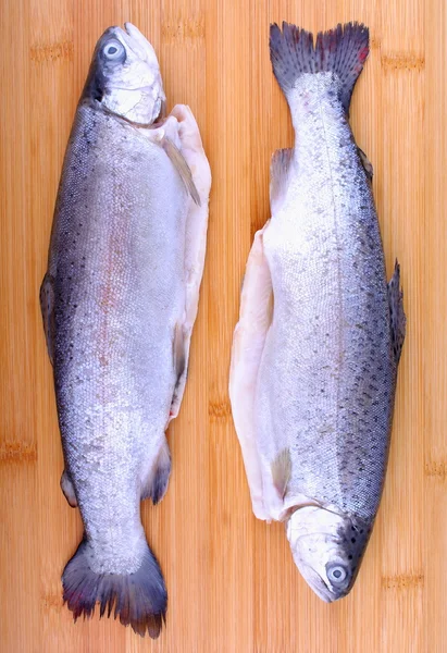 Two whole fresh trout on bamboo cutting board — Stock Photo, Image