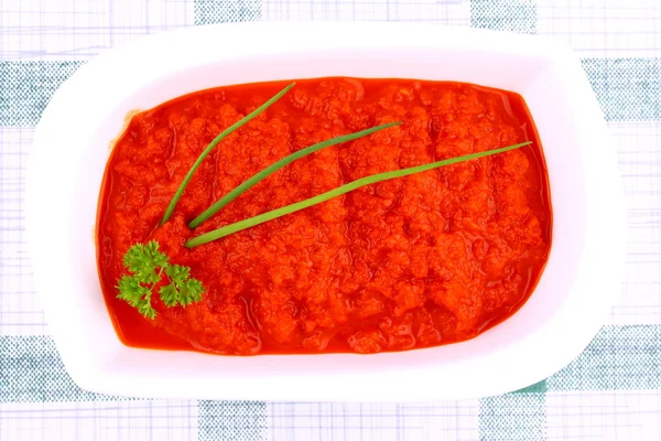 Bright red ajvar in white bowl, parsley, spring onion — Stock Photo, Image