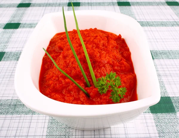 Red ajvar in white bowl with parsley, spring onion — Stock Photo, Image