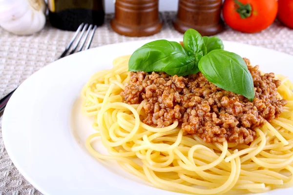 Pyszne spaghetti bolognese z bazylią na białym talerzu — Zdjęcie stockowe