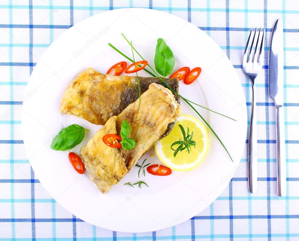 Dos filetes de pescado frito con rodaja de limón en un plato blanco 2023