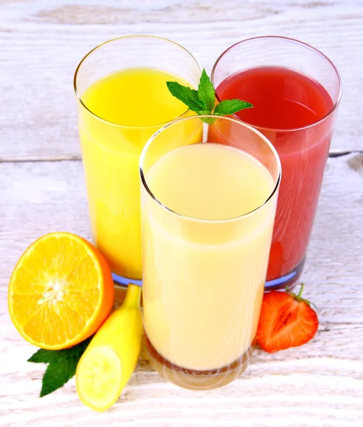 Plátanos, rodajas de fresa y naranjas, jugo en vaso — Foto de Stock