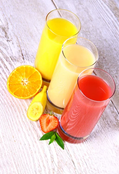 Naranjas, plátanos, rodajas de fresa y jugo en vaso — Foto de Stock