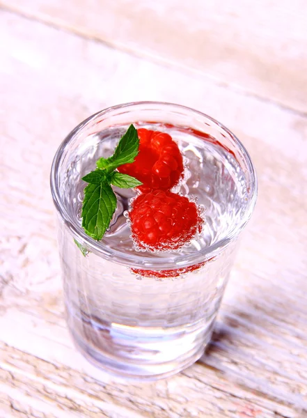Água em vidro com hortelã e duas framboesas — Fotografia de Stock