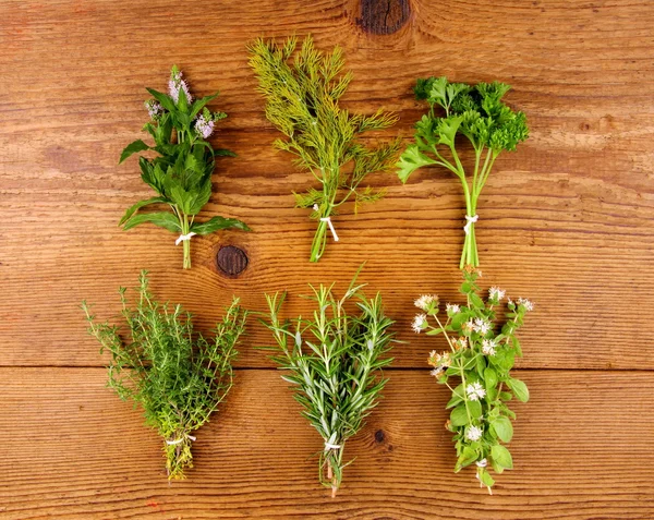 Herbs in bundle on brown wooden background, top view — Stock Photo, Image