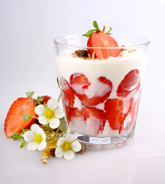 Jordgubbar med yoghurt i glas, blommor och flingor — Stockfoto