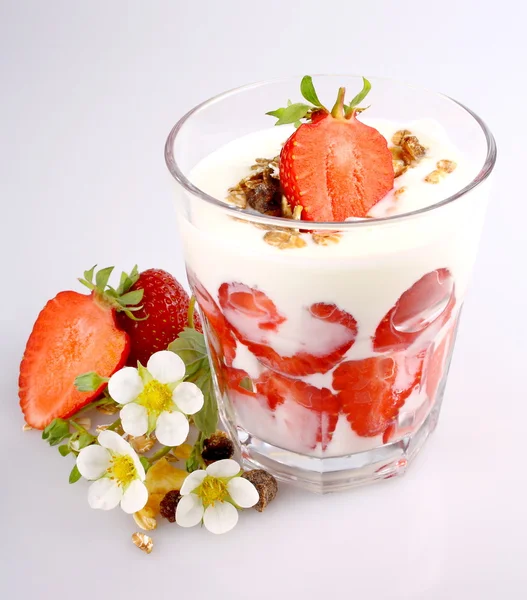 Jordgubbar med yoghurt i glas, spannmål och blommor — Stockfoto