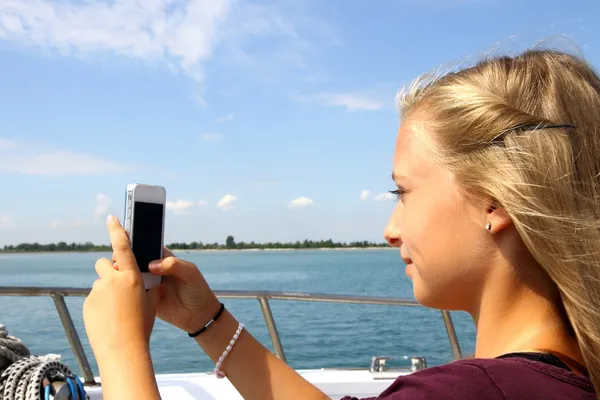 Smiling blond girl with phone on the boat
