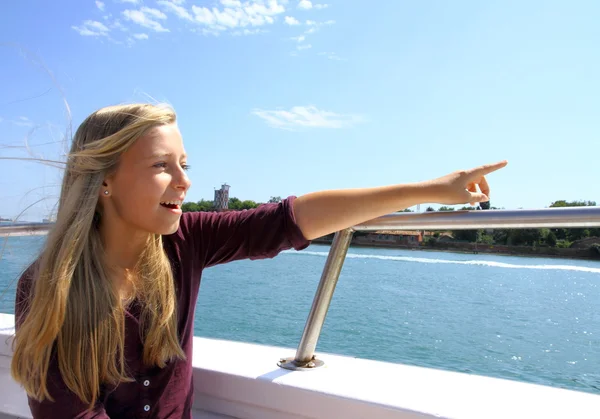 Cheerful young blonde girl shows target on ship at sea — Stock Photo, Image