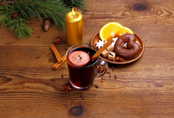 Vinho amontoado em vidro com pau de canela, vela e doces — Fotografia de Stock