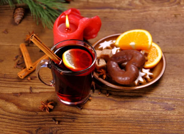 Vino caliente en vaso con varilla de canela, vela y dulces — Foto de Stock