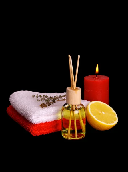 Botella amarilla con aceite esencial, velas y toallas de baño —  Fotos de Stock