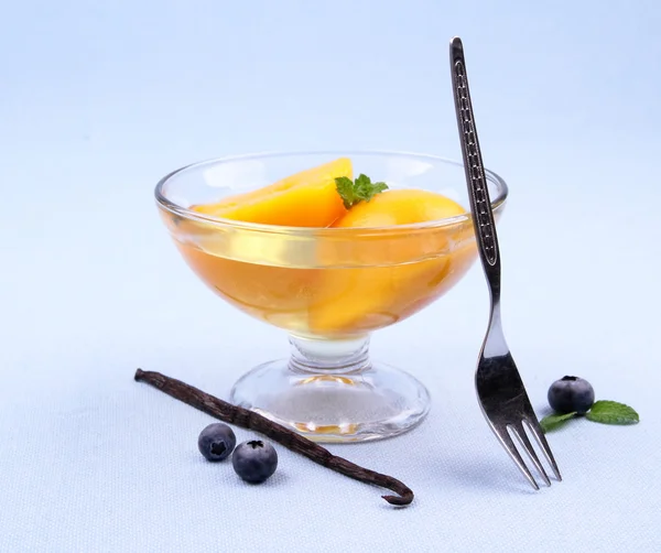 Perzik compote in glazen kom met een vork, bosbessen en vanille — Stockfoto