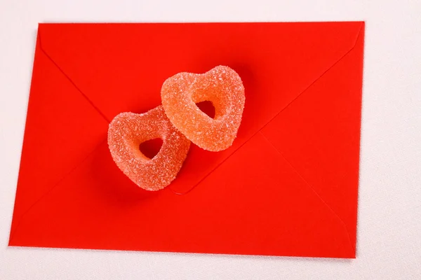 Two hearts from sugar candies on red envelope — Stock Photo, Image