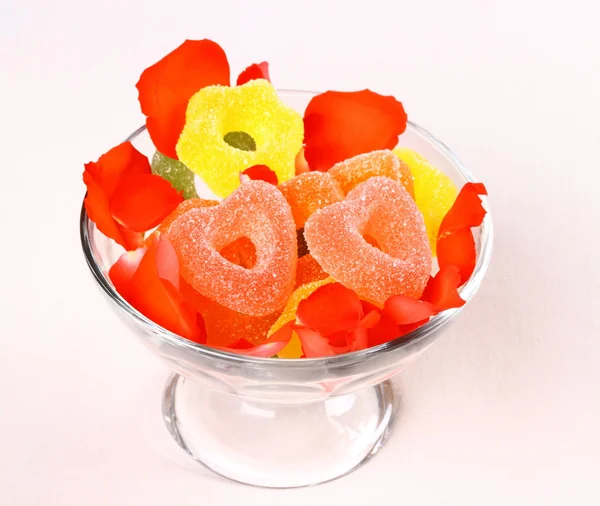 在玻璃碗和玫瑰花瓣的两个红心糖果。 — 图库照片