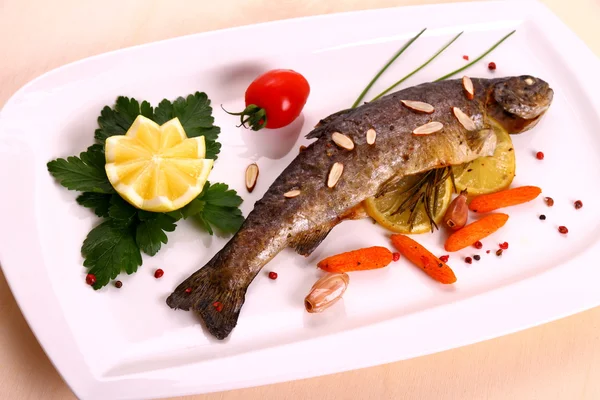 Trota fritta con limone e mandorle spezzate su piatto bianco — Foto Stock