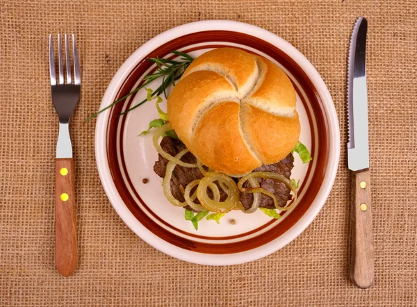 Grilled beef with onion rings in bun — Stock Photo, Image