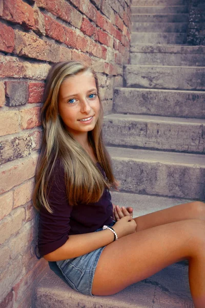Cute girl sitting on brick steps — Stock Photo, Image