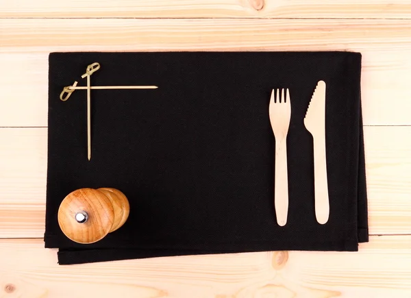 Wood cutlery on black placemat as menu board — Stock Photo, Image