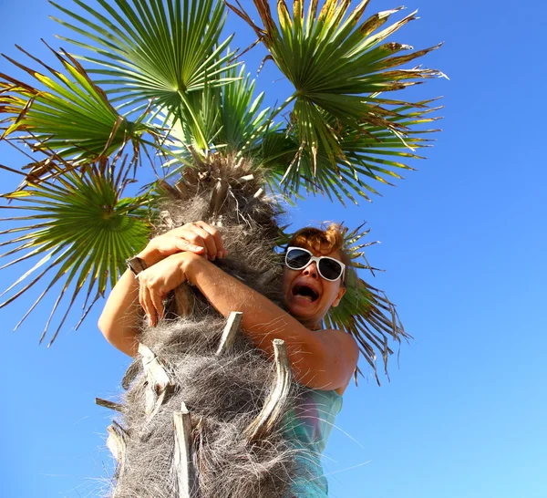 Mature woman sits on palm tree, scared — Stock Photo, Image