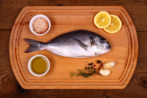 Fresh bream fish on cutting board with ingredients — Stock Photo, Image