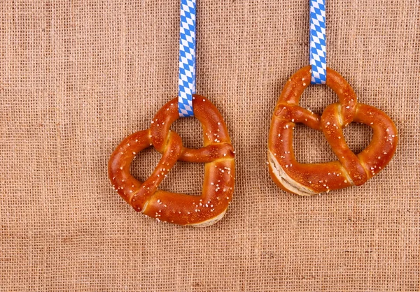 Two pretzel in heart shape on jute background — Stock Photo, Image