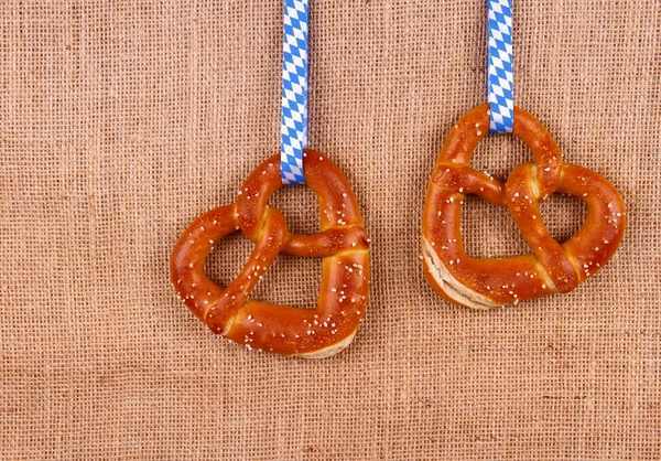 Dois pretzel em forma de coração no fundo de juta — Fotografia de Stock