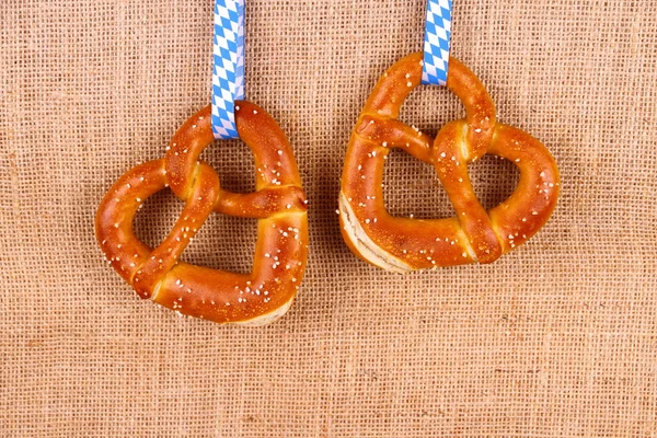 Two pretzel in heart shape on jute background — Stock Photo, Image