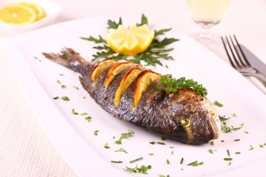 ızgara çipura balık, limon, roka beyaz plaka üzerinde