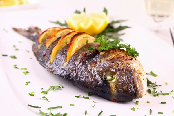 Grilled sea bream fish, lemon, arugula on white plate — Stock Photo, Image