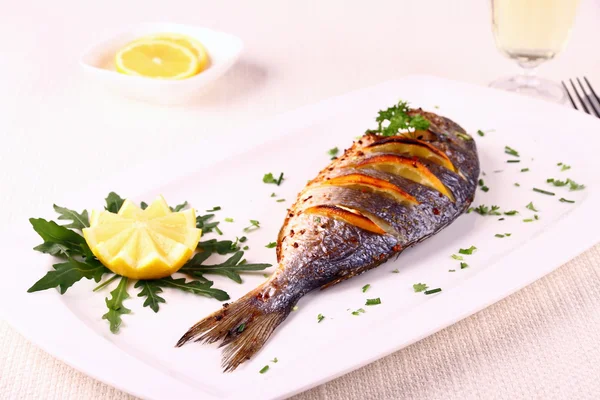 Pesce sarago alla griglia, limone, rucola su piatto bianco — Foto Stock