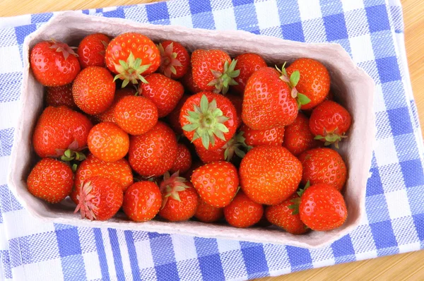 Verse aardbeien in papier vak op wit-blauwe achtergrond — Stockfoto