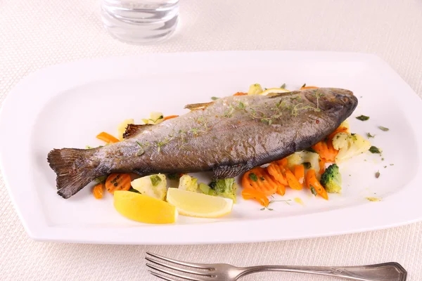 Fried whole trout, vegetables and cutlery — Stock Photo, Image