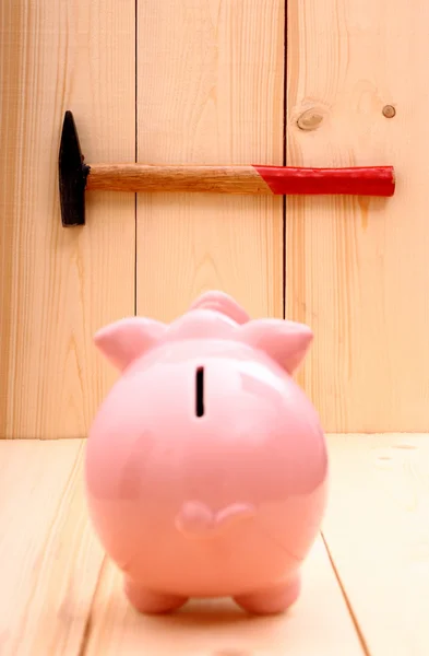 Funny pink piggy bank and hammer in focus on wood — Stock Photo, Image