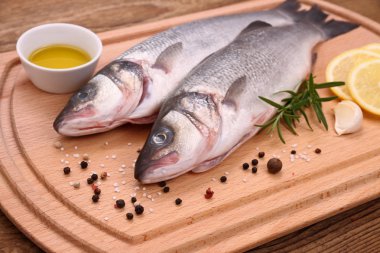 malzemeler ile kesme tahtası üzerinde iki taze levrek balığı