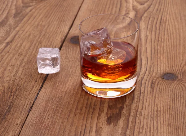 Whiskey with ice cubes in glass on wood background — Stock Photo, Image
