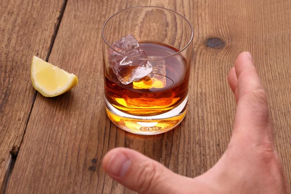Whiskey with ice cubes in glass and grab hand — Stock Photo, Image