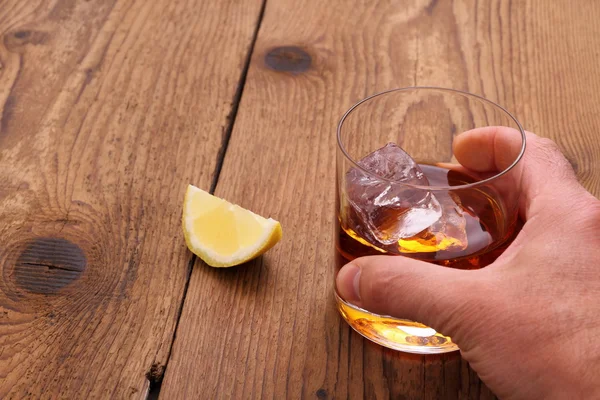 Whiskey with ice cubes in glass with grab hand — Stock Photo, Image