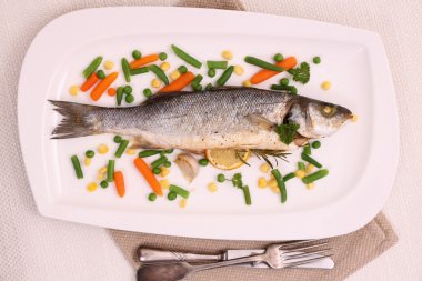 Fried whole sea bass with vegetables and lemon clipart