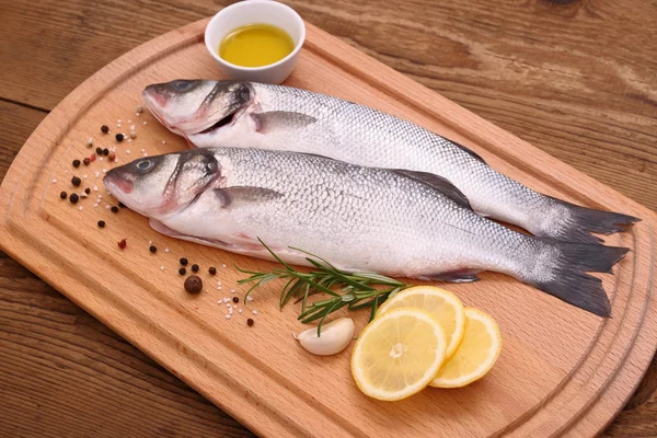 Two fresh sea bass fish on cutting board — Stock Photo, Image