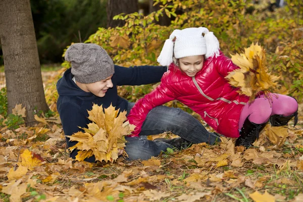 Kinder spielen mit herbstlichem Laub — Stockfoto