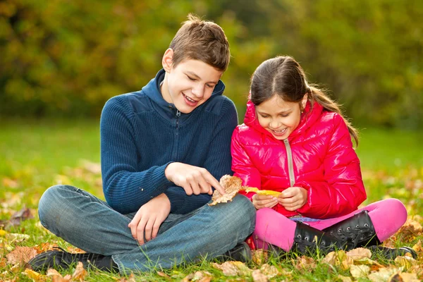 Děti si hrají s podzimní listí — Stock fotografie