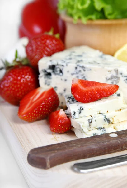 Aardbeien en kaas op een houten bord — Stockfoto