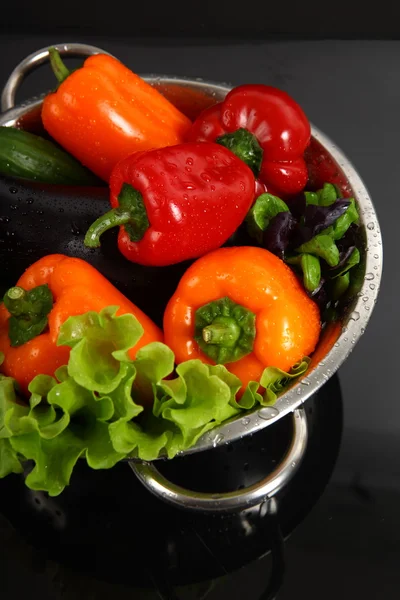 Frisch gewaschenes frisches Gemüse in einem Metallsieb isoliert über schwarzem Hintergrund — Stockfoto
