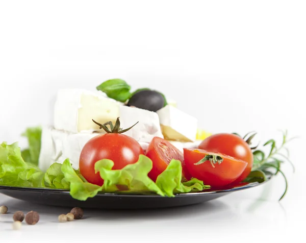 Cherry tomatoes and cheese on a wooden plate — Stock Photo, Image